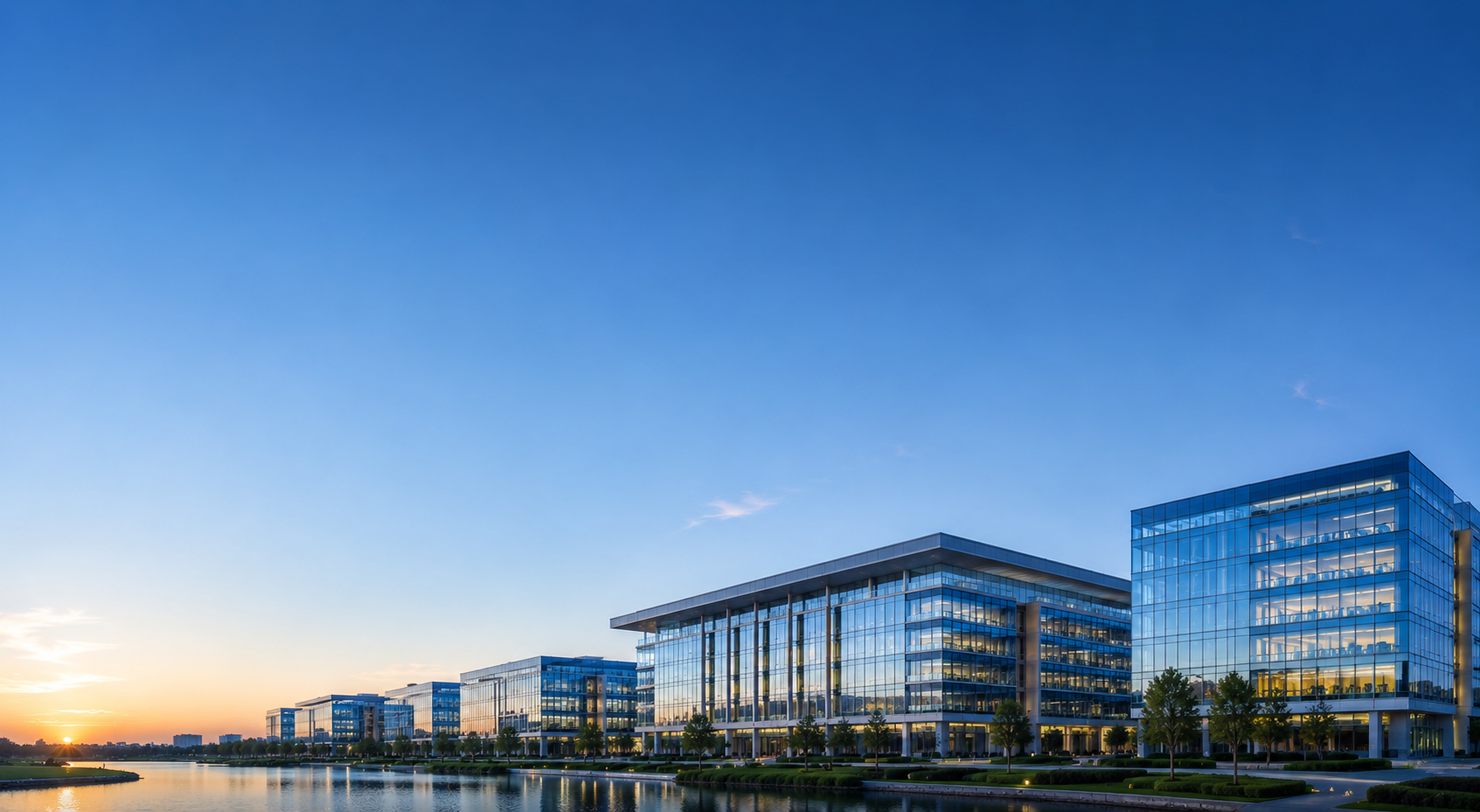Modern glass technology campus buildings lit at dusk beside water